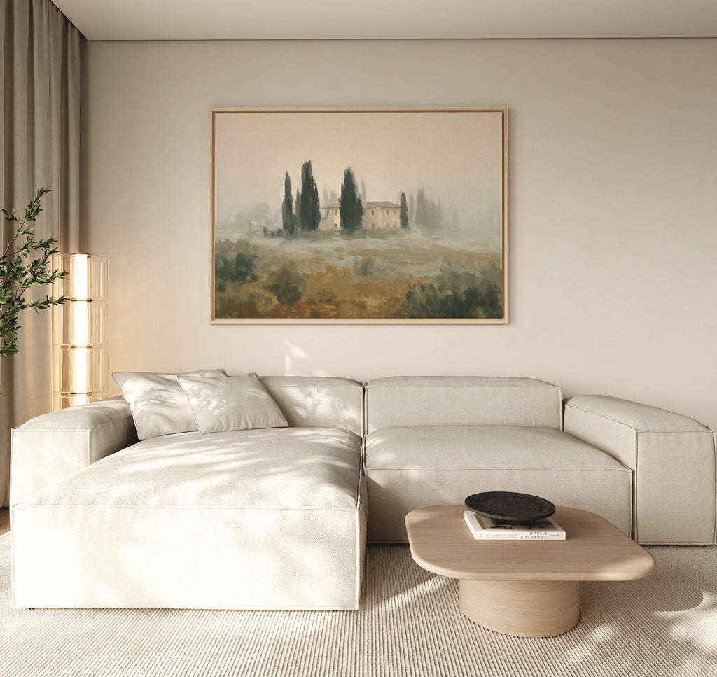 A modern living room features a light beige sectional, wooden coffee table, potted plant, and the Tuscan Veil Canvas Art - Horizontal on the wall. Soft lighting and neutral tones evoke a cozy Mediterranean-inspired atmosphere.
