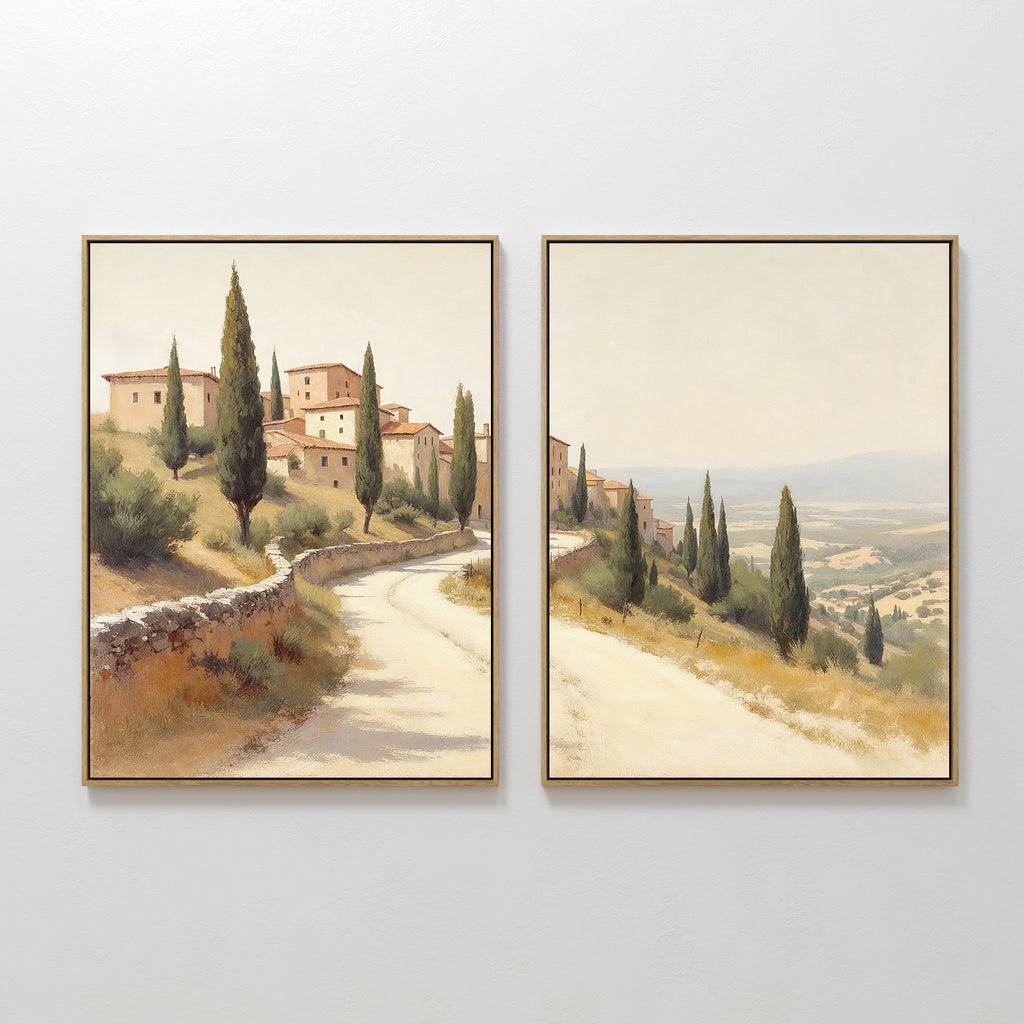 The "Tuscan Village - Set of 2" features canvas prints of a winding road through stone buildings and cypress trees under a hazy sky, creating connected scenes for charming rustic Mediterranean wall art.