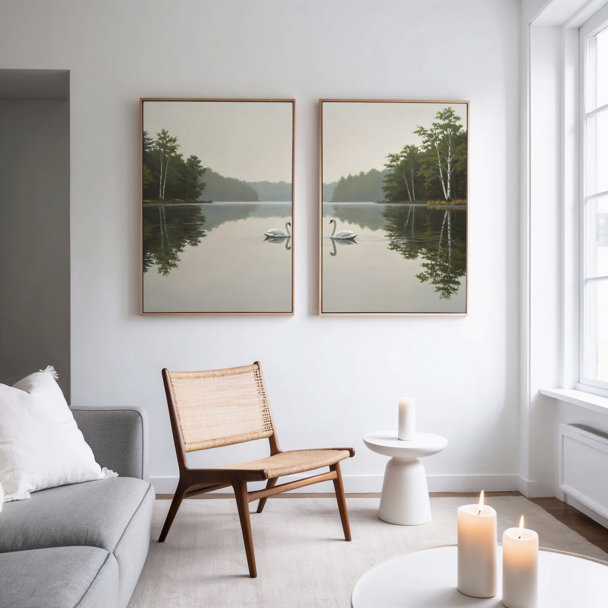 A modern living room featuring a gray sofa, wooden chair, glowing candles, and the "Twin Swans Serenity - Set Of 2" wall art—ideal Nordic decor—by a large window that fills the space with natural light.
