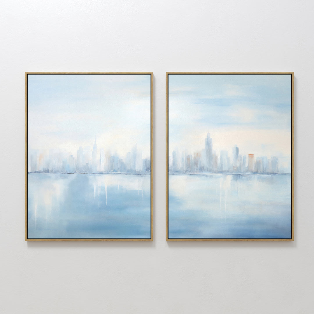 Urban Mirage - Set of 2 features square canvas prints with a soft, abstract city skyline reflected over water in pale blue, white, and peach—ideal wall art for modern living room décor.