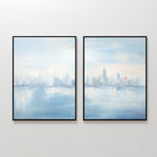 The Urban Mirage - Set of 2 features framed canvas prints of a blurred blue and white city skyline with water reflections, displayed side by side—an ideal modern accent for your living room wall.