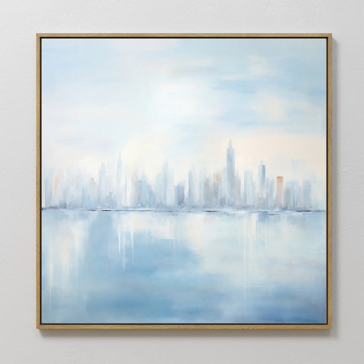 Urban Mirage Canvas Art - Square features a city skyline reflected in water, rendered in soft blue and white tones. This dreamy urban wall decor adds a calm, modern touch to your living room. Framed and ready to hang.