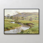 The Valley Stream Canvas Art - Horizontal displays a peaceful countryside with a winding river, green fields, scattered trees, and gentle hills under a partly cloudy sky, beautifully framed and shown on a plain white wall.