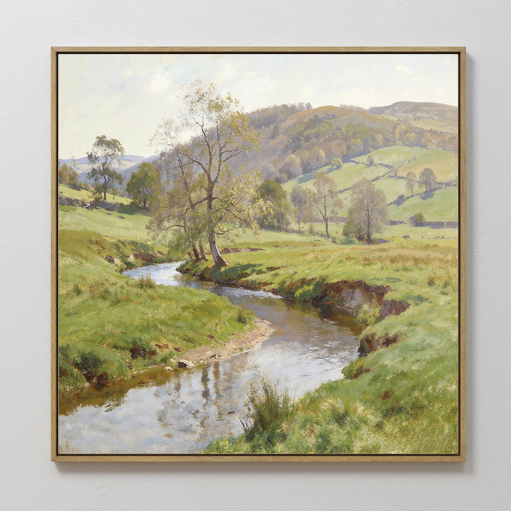 The Valley Stream Canvas Art - Square showcases a framed countryside landscape with a winding river, grassy fields, scattered trees, rolling hills, and a partly cloudy sky.