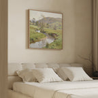 A cozy bedroom with a beige upholstered bed, four white pillows, light bedding, and the Valley Stream Canvas Art - Square featuring a serene green countryside with a river and hills hanging above the headboard.