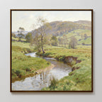 The Valley Stream Canvas Art - Square features a framed serene landscape with a curving river, green banks, scattered trees, rolling hills, and a partly cloudy sky for a peaceful rural vibe.