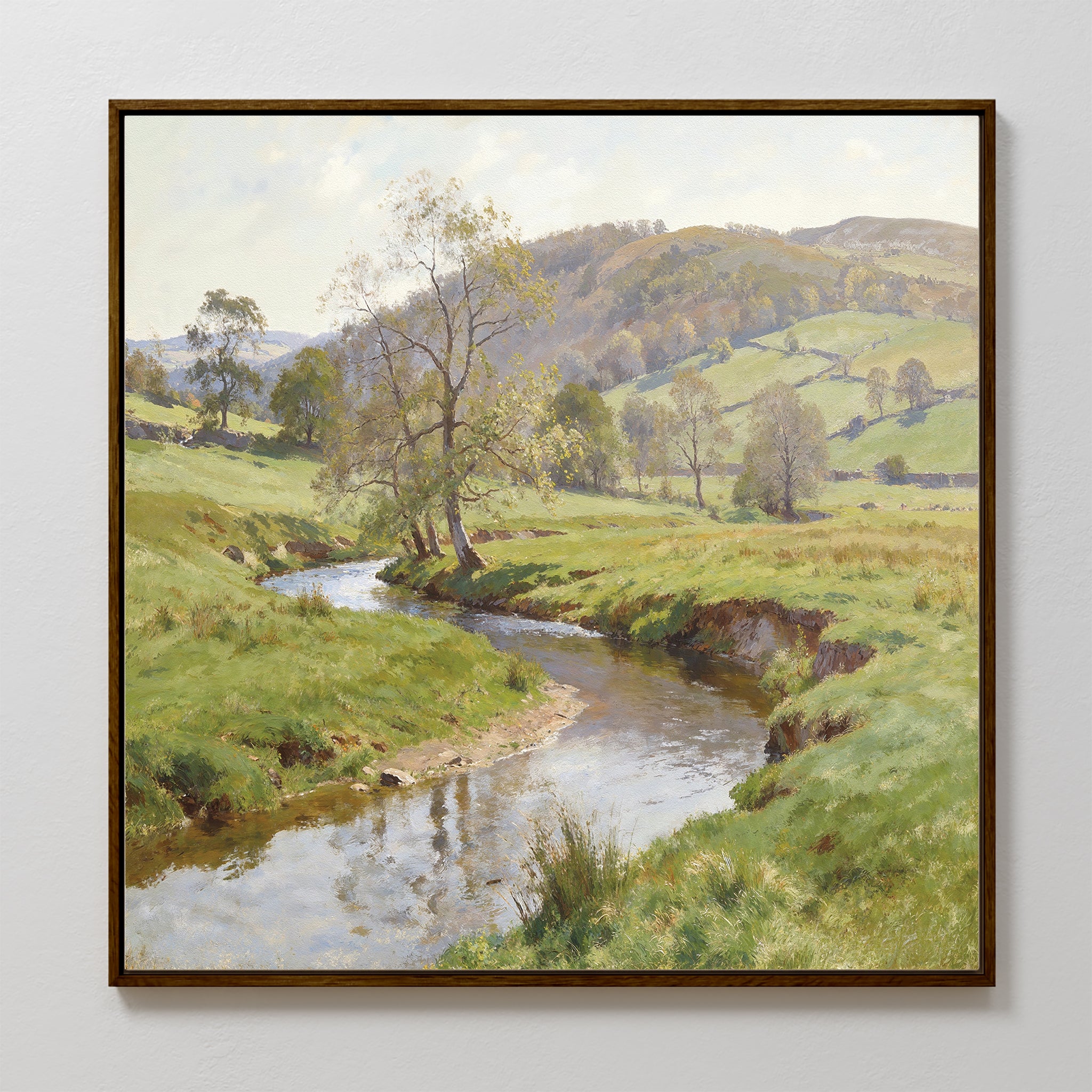 The Valley Stream Canvas Art - Square features a framed serene landscape with a curving river, green banks, scattered trees, rolling hills, and a partly cloudy sky for a peaceful rural vibe.