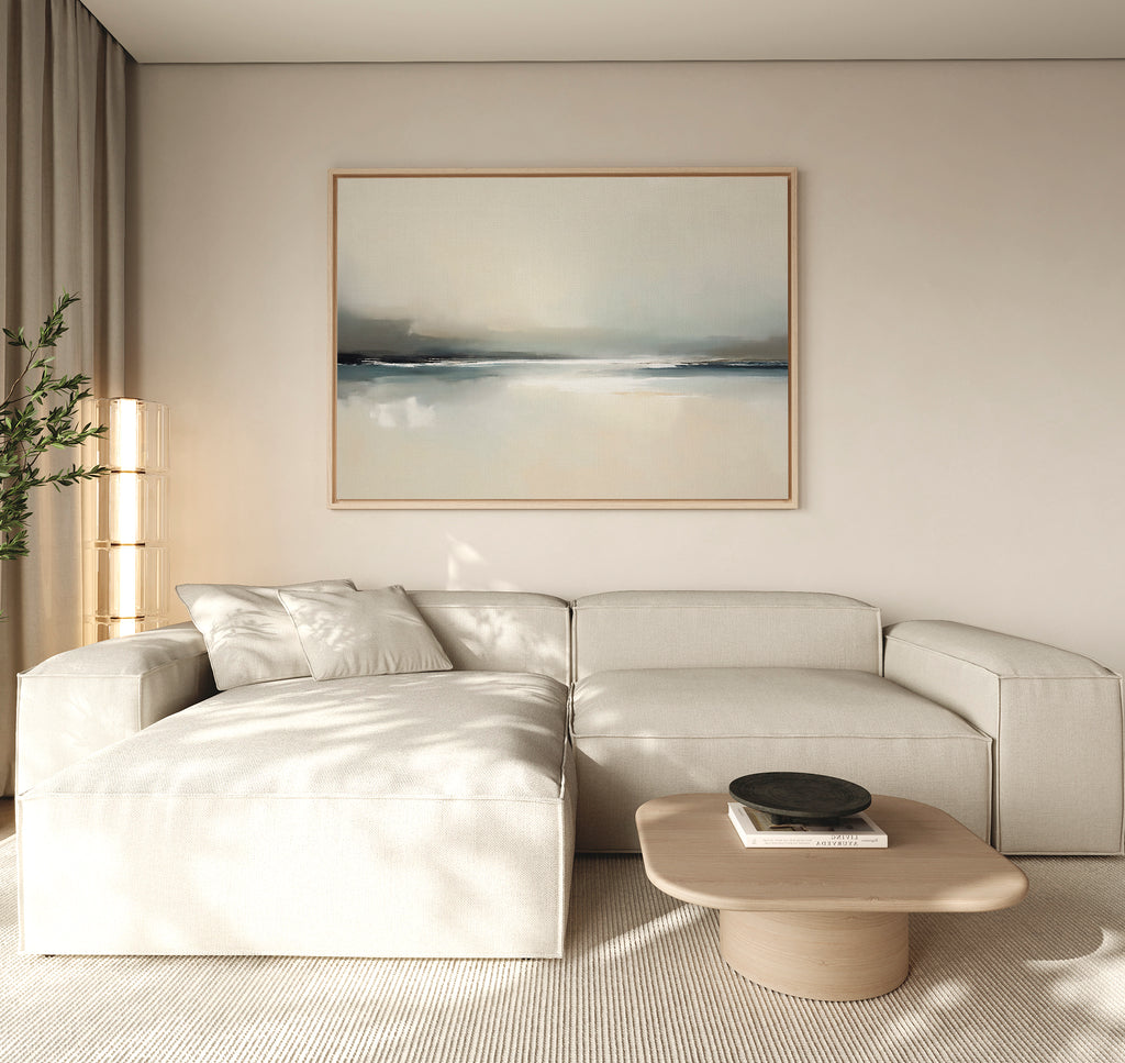 A modern living room with a light beige sectional, a square wooden coffee table with a dark bowl, and beige curtains, highlighted by the Veiled Estuary Canvas Art - Horizontal above the sofa.