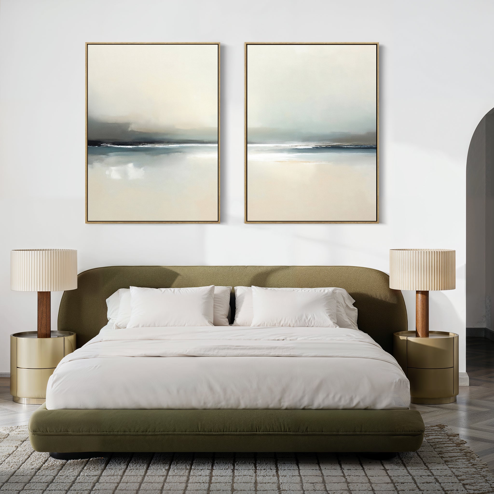 A modern bedroom with a green upholstered bed, white bedding, and two beige nightstands features Veiled Estuary - Set Of 2 serene landscape prints above the headboard. The room’s neutral palette enhances its cozy atmosphere.