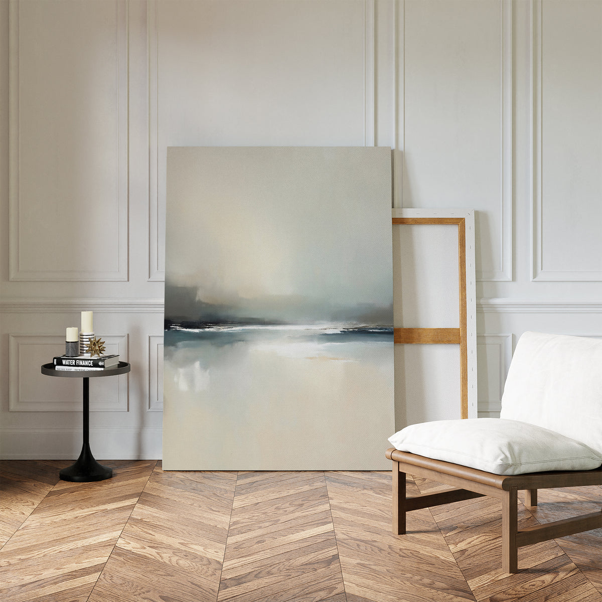 A minimalist living space with herringbone wood floors, a cushioned wooden chair, a small round black table with candles and books, and the Veiled Estuary Canvas Art - Vertical leaning against a white paneled wall.