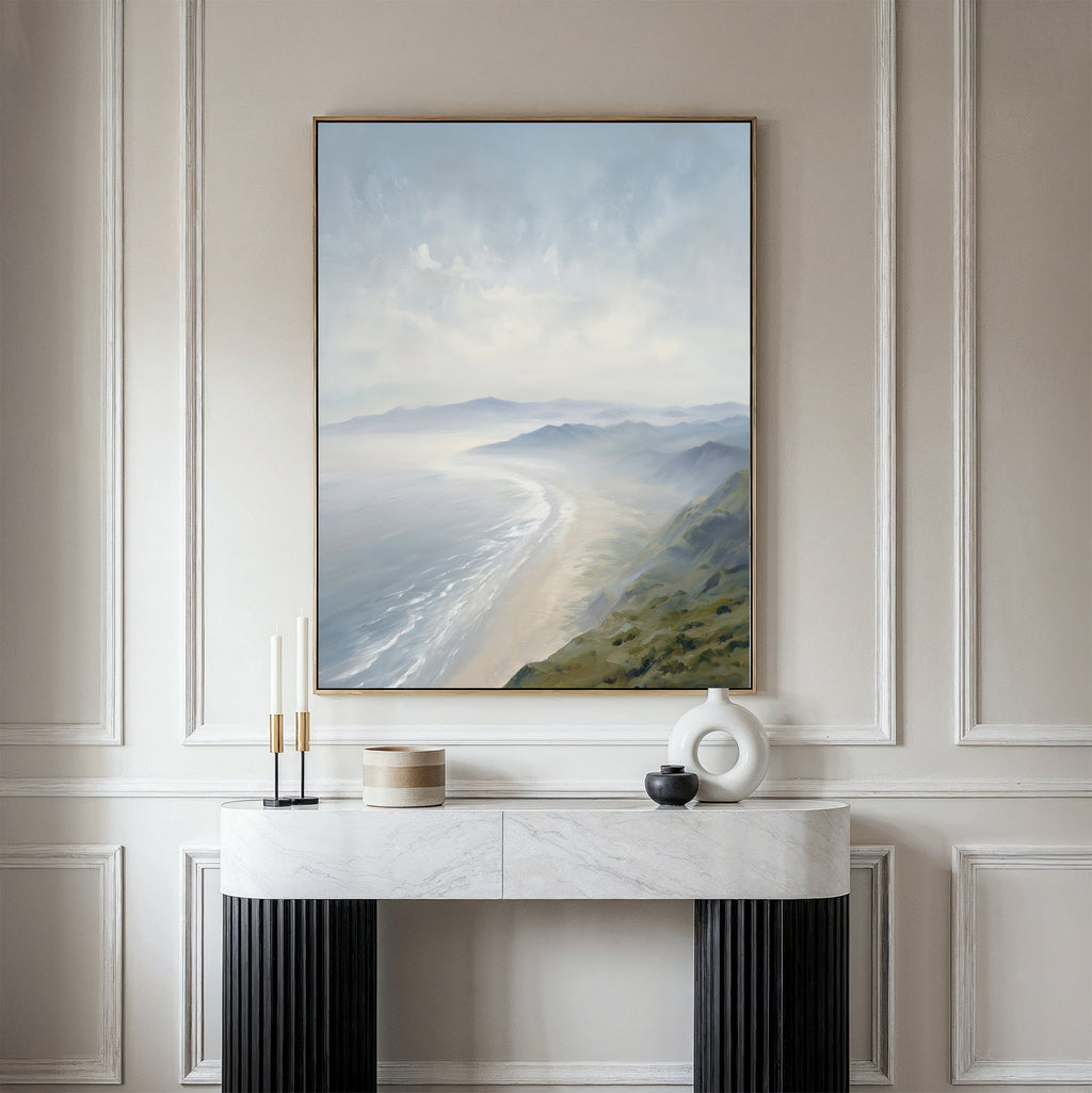 The Veiled Shores Canvas Art - Vertical hangs on a light wall above a marble console with black legs, accented by candles and modern ceramic vases, creating a serene display of tranquil wall art.