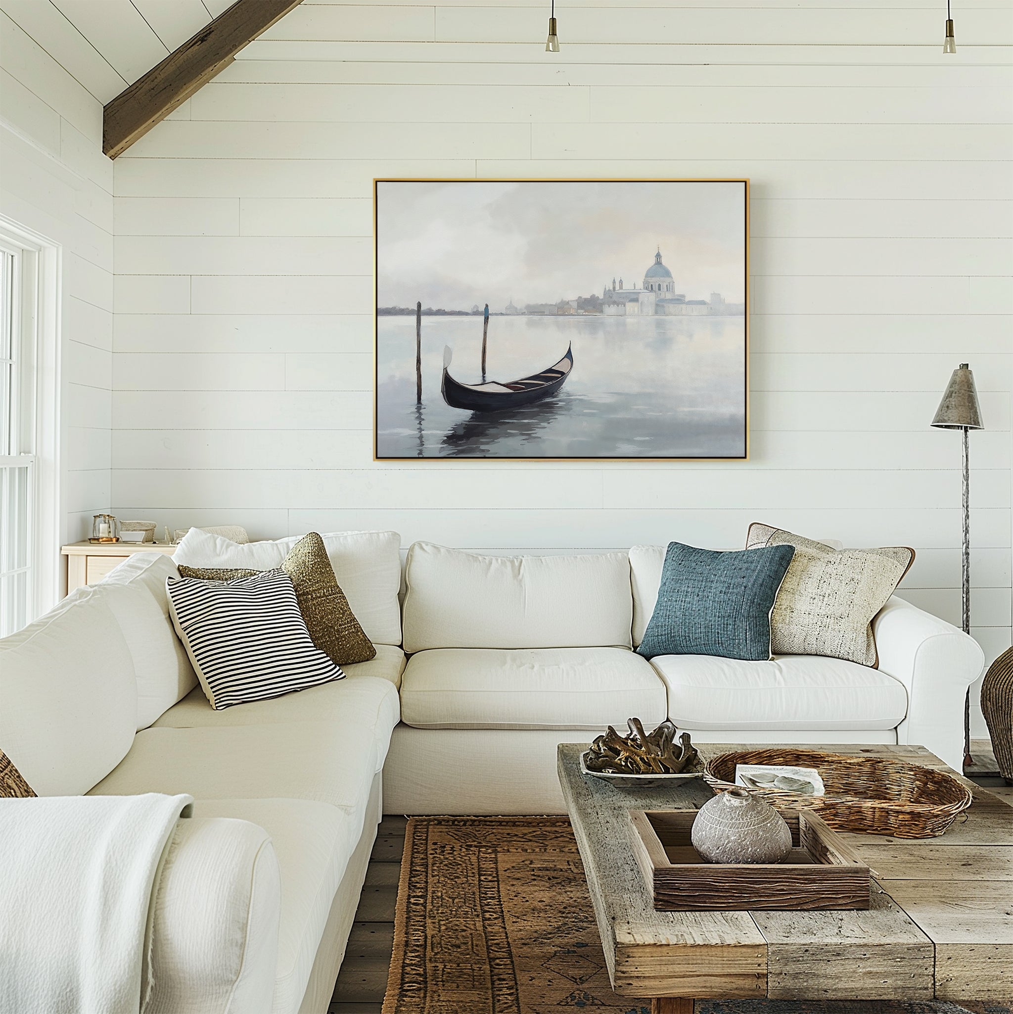 A bright, cozy living room features a white sectional sofa with pillows, a rustic wooden coffee table, and the Venetian Stillness Canvas Art - Horizontal displayed on a white shiplap wall.