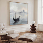 A modern living room featuring a white lounge chair, dark wood side table, and the "Venetian Stillness Canvas Art - Square" brings unmistakable European charm to the serene space.
