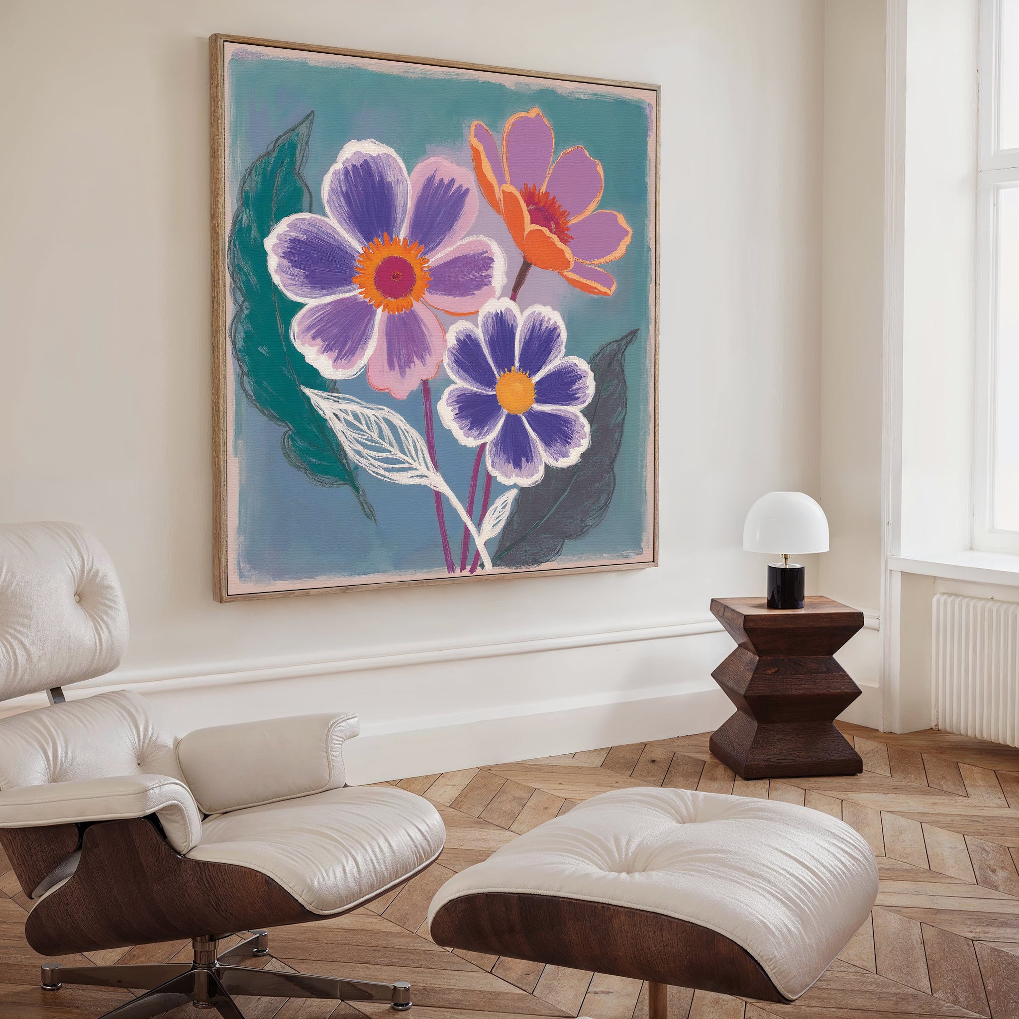 A stylish living room features a white leather lounge chair and ottoman, a modern dark wood side table, and the Vibrant Petals Canvas Art - Square as bold wall décor. Sunlight from a tall window enhances this Nordic Park-inspired cozy space.