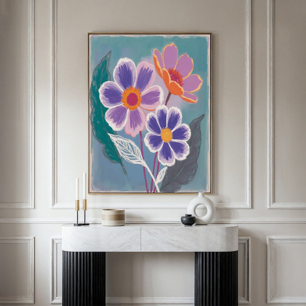 The Vibrant Petals Canvas Art - Vertical, a framed botanical print of colorful flowers, hangs on a light gray wall above a modern console table with a white marble top and black textured legs, adorned with minimalist candle holders and ceramic objects.