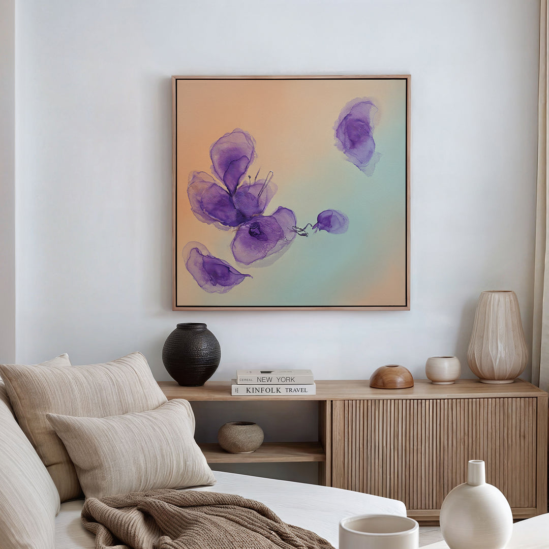 A modern living room with a beige sofa, neutral cushions, and a wooden sideboard decorated with vases and books. Above the sideboard hangs the Violet Dreams Canvas Art - Square, adding botanical charm with its abstract floral design.