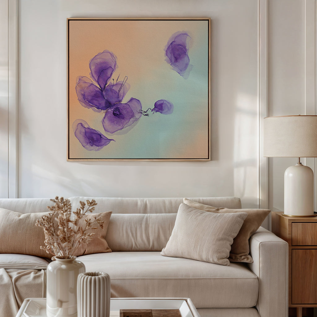 A modern living room features a white sofa with beige and white cushions, a side table with a lamp, and dried flowers. Above the sofa hangs the Violet Dreams Canvas Art - Square, showcasing purple watercolor flowers for an elegant touch.