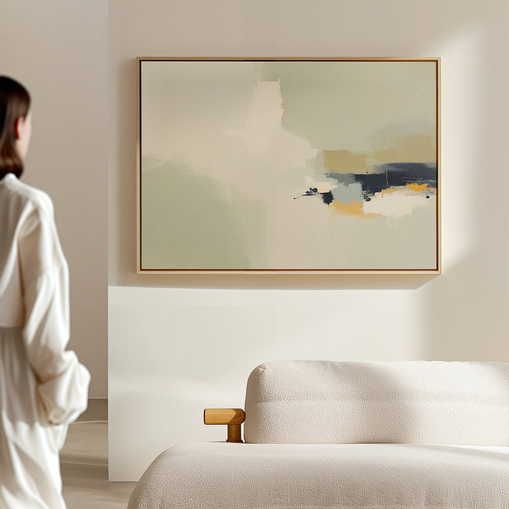 A person in a white shirt admires the Weathered Composition Canvas Art - Horizontal, an abstract print in soft beige, blue, and orange tones, displayed above a light sofa in a minimalist room that exudes modern elegance.