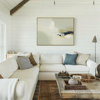 A cozy living room features a white sectional sofa, assorted throw pillows, a rustic wooden coffee table with décor, and modern elegance with the Weathered Composition Canvas Art - Horizontal on a white shiplap wall. Warm neutrals create a relaxed atmosphere.
