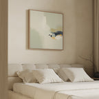 A modern, minimalist bedroom features a beige upholstered bed with white pillows and bedding. Above the headboard hangs the Weathered Composition Canvas Art - Square, while a bare branch on the side table enhances the contemporary elegance.