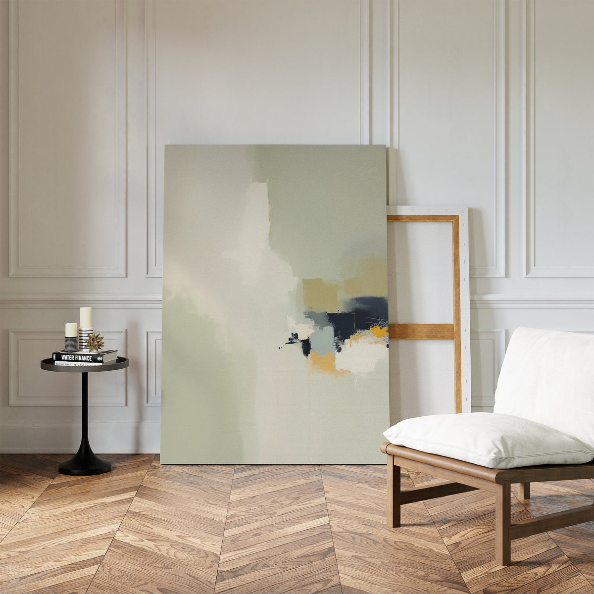 A minimalist living space features a white cushioned chair, a round black side table with candles and books, and the Weathered Composition Canvas Art - Vertical resting against a paneled white wall on a parquet wood floor.