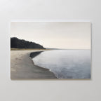 Weathered Shore Canvas Art - Horizontal depicts a calm beach with gentle waves, a curving sandy coastline, and trees under an overcast sky—ideal shoreline wall art for serene spaces.