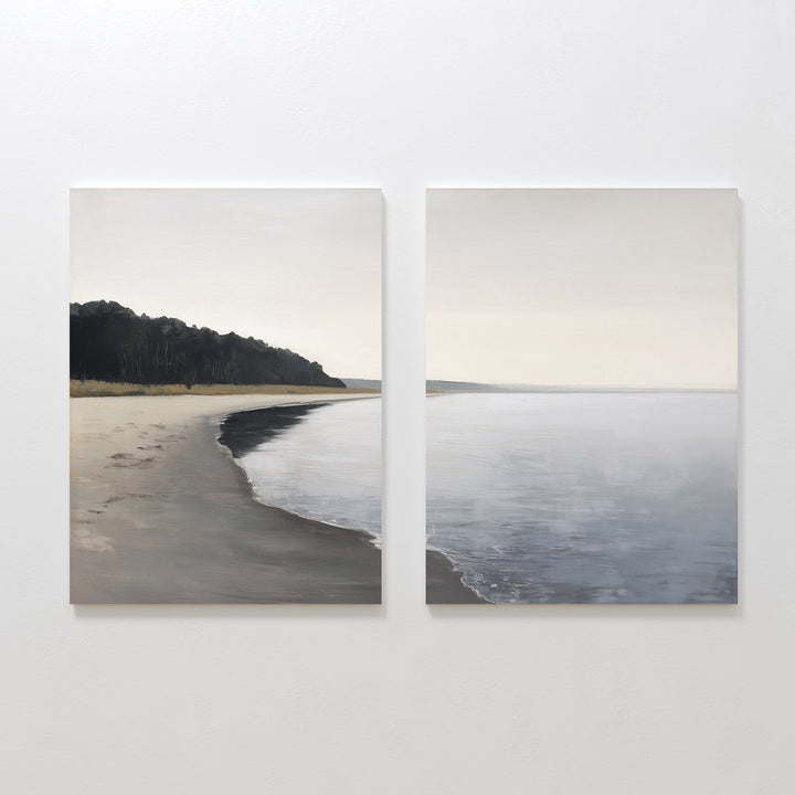 Weathered Shore - Set of 2 features minimalist coastal canvas prints of a calm beach with gentle waves, sandy shoreline, and distant trees. Soft, muted colors create a serene vibe—ideal shoreline wall art to bring tranquility to your space.
