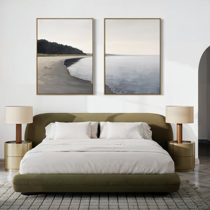 A modern bedroom features a low olive-green bed with white bedding, two round gold nightstands topped with beige lamps, and the "Weathered Shore - Set of 2" shoreline wall art pieces displayed above the headboard.