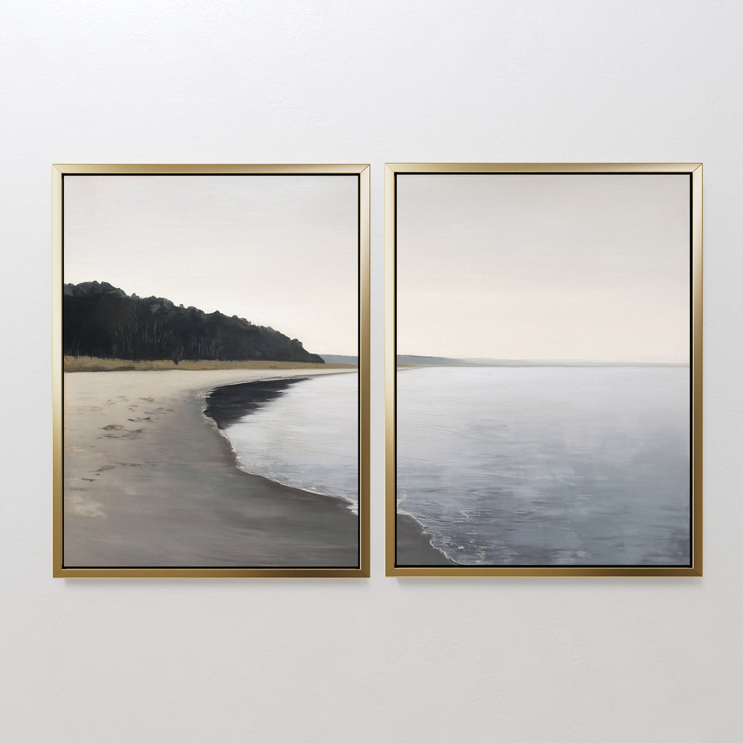 The Weathered Shore - Set of 2 features framed coastal canvas prints with gentle waves, a distant treeline, and muted neutral tones beneath a soft cloudy sky—perfect shoreline wall art for a serene space.