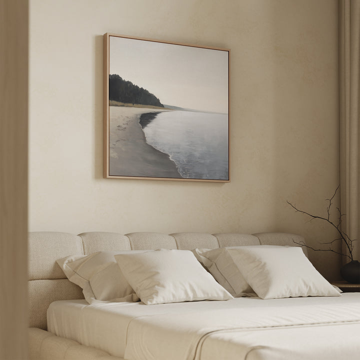 A minimalist bedroom features a beige upholstered bed, cream bedding, and the Weathered Shore Canvas Art - Square above the headboard. Neutral walls and a simple branch in a vase complete the calm, serene decor.