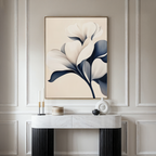 A modern living room highlights the Navy Magnolia Canvas Art—a large, minimalist piece with abstract blue and white flowers—above a marble console table adorned with vases and candles. Elegant light wall paneling completes the decor.