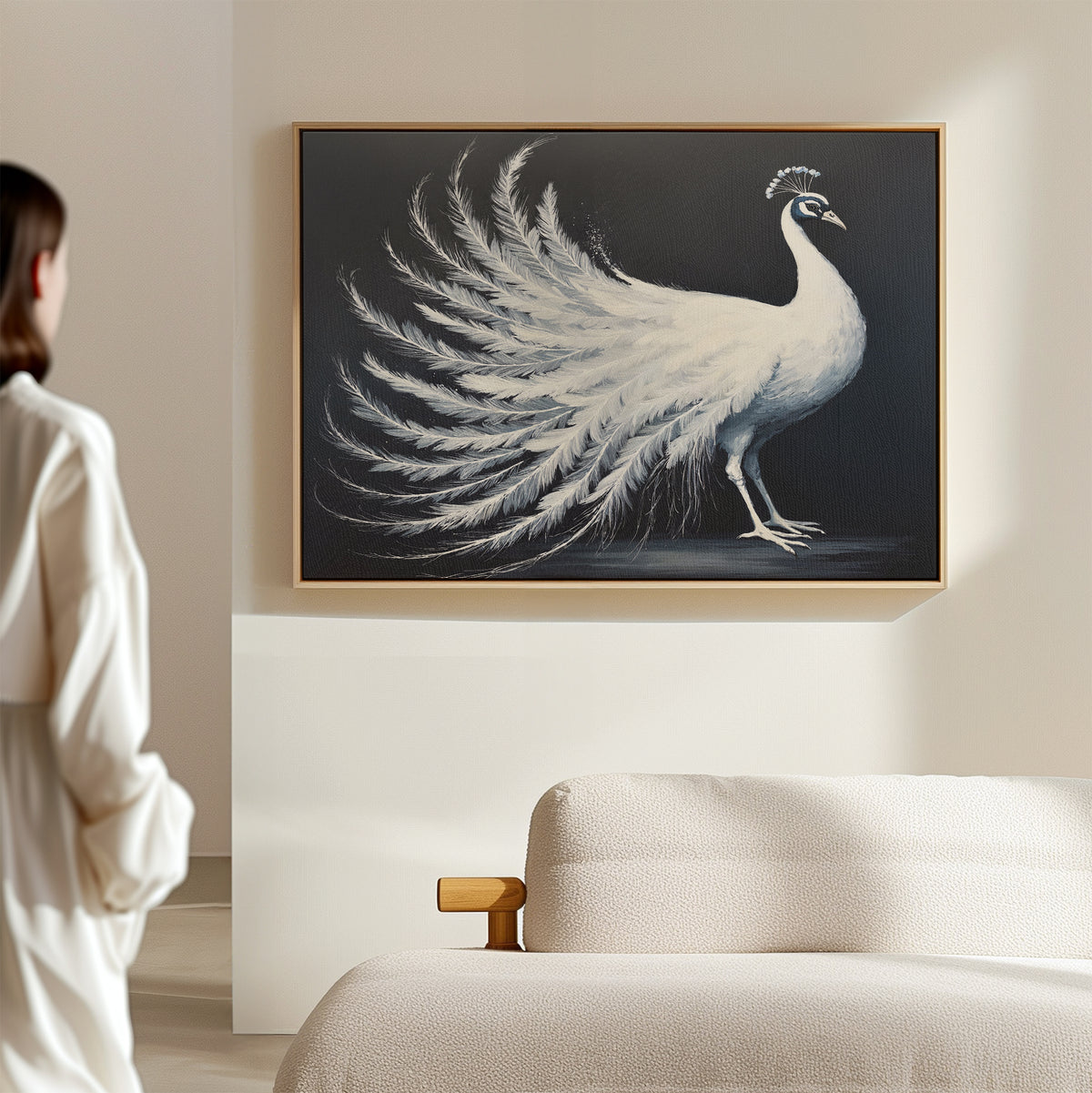 A woman in white admires the White Peacock Display Canvas Art - Horizontal, elegantly framed and displayed above a beige sofa in a modern, softly lit living room.