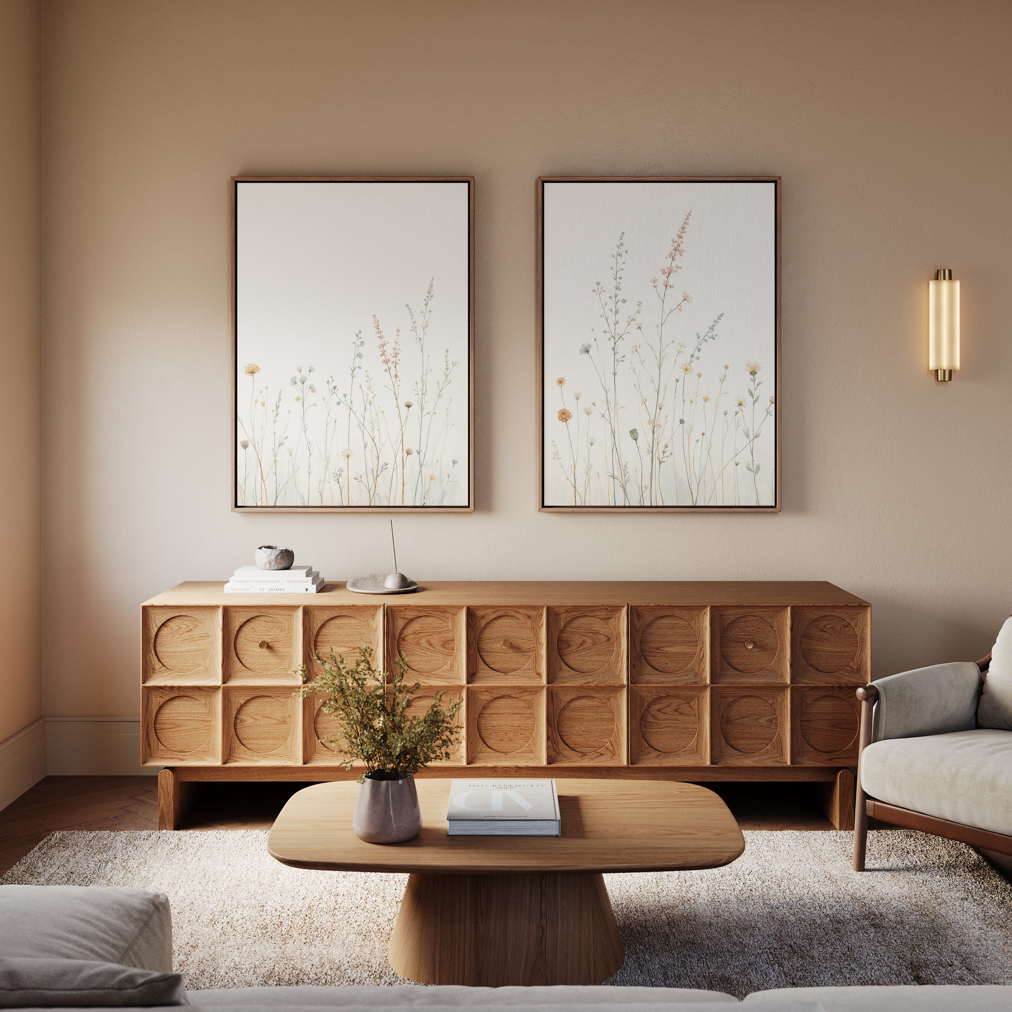 A modern living room with a wooden sideboard, matching coffee table, and light gray sofa. Above the sideboard hangs Wildflower Dreams - Set of 2 botanical wall art, while flowers in a vase add fresh charm to the coffee table.