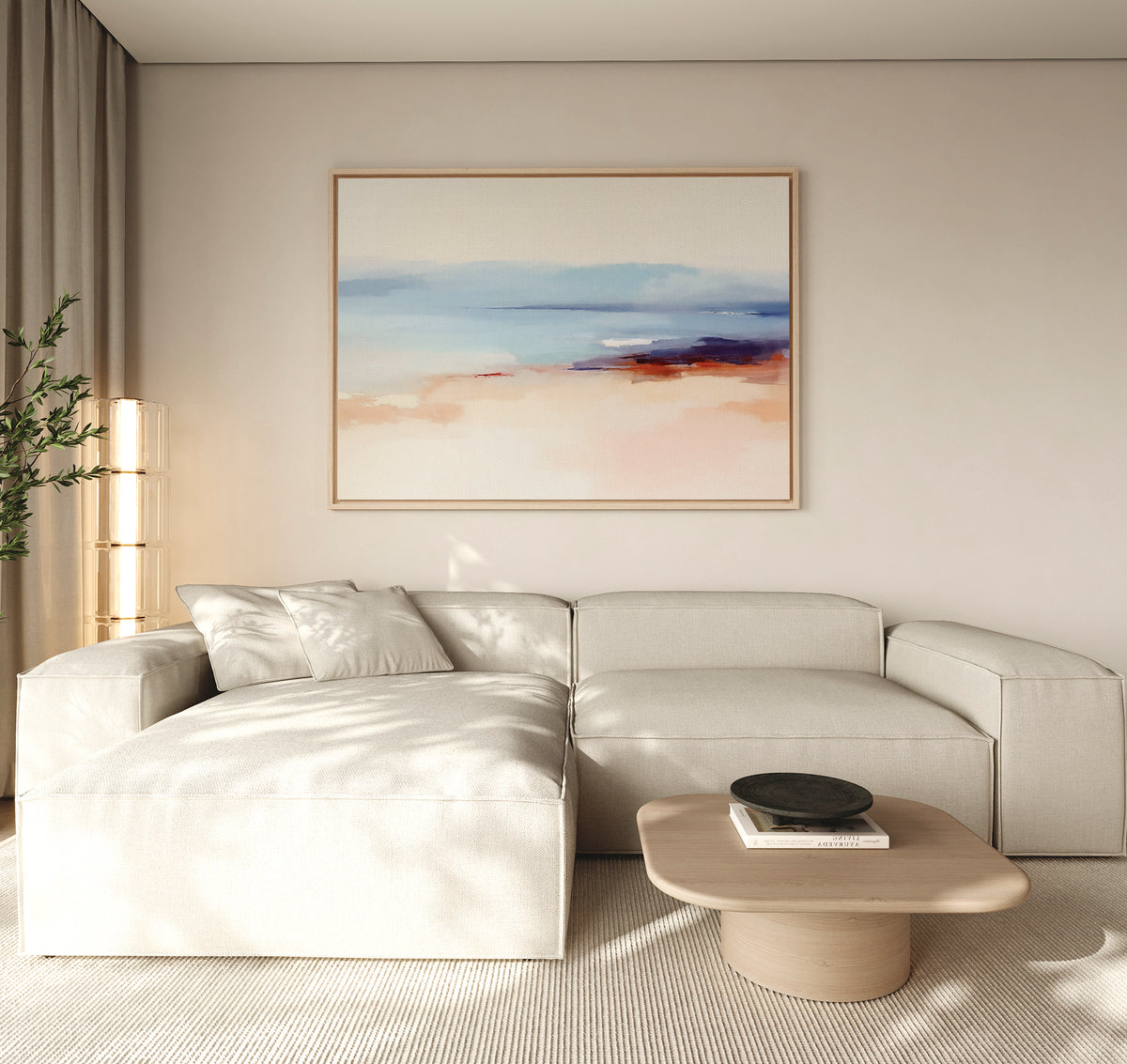 A modern, minimalist living room with a beige sectional, light wood coffee table with a black bowl, tall plant, neutral walls and curtains, and the Windswept Coastline Canvas Art - Horizontal on the wall.
