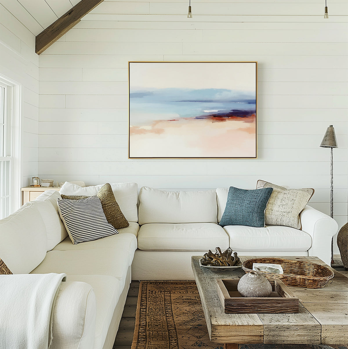 A cozy living room with white shiplap walls, a white sectional sofa, and a rustic wooden coffee table features the Windswept Coastline Canvas Art - Horizontal above the sofa, creating a relaxed and breezy coastal vibe.