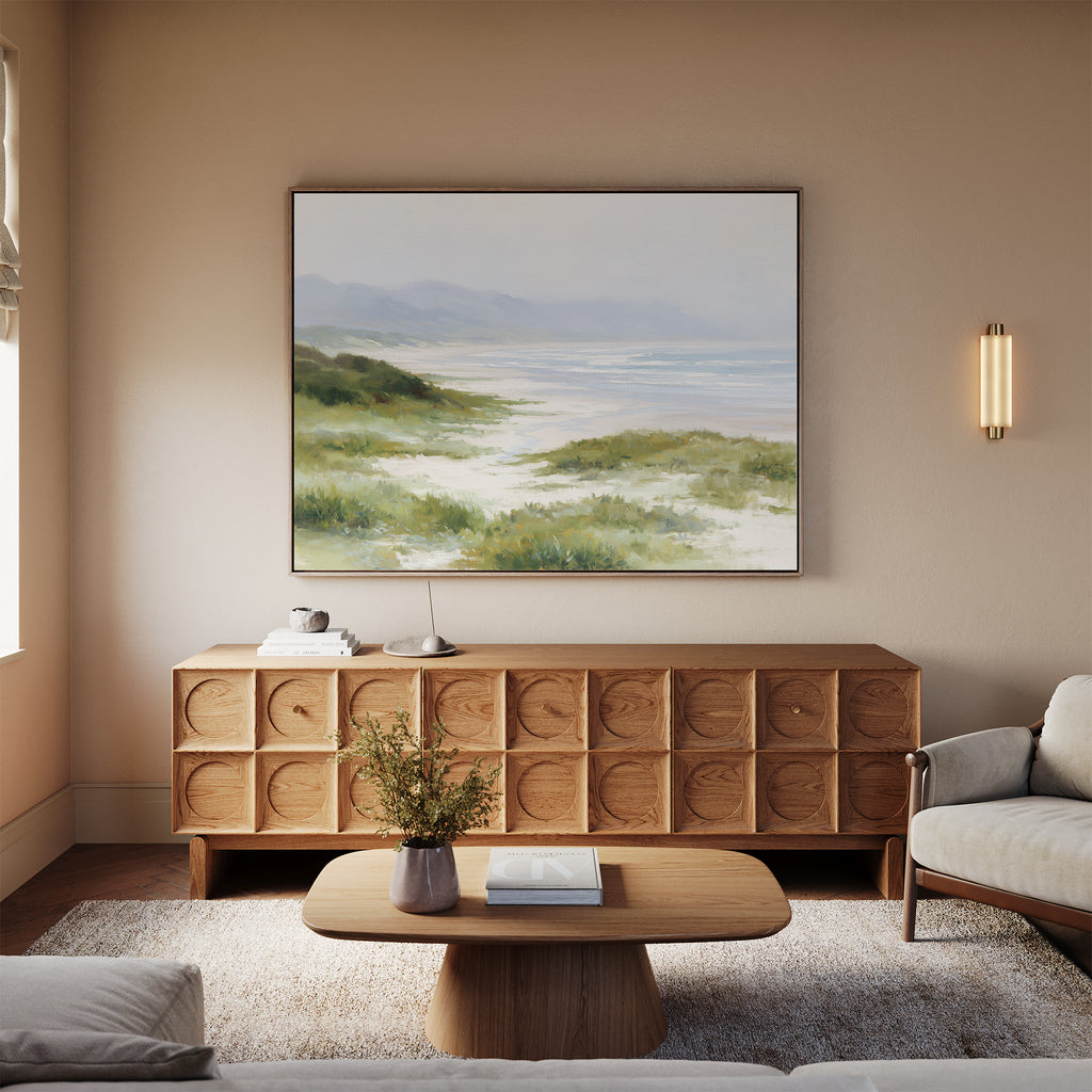 A cozy living room features a light wood credenza, coffee table, and neutral sofas. Windswept Dunes Canvas Art - Horizontal hangs above the credenza, with a modern wall sconce and fresh flowers adding a calming touch.