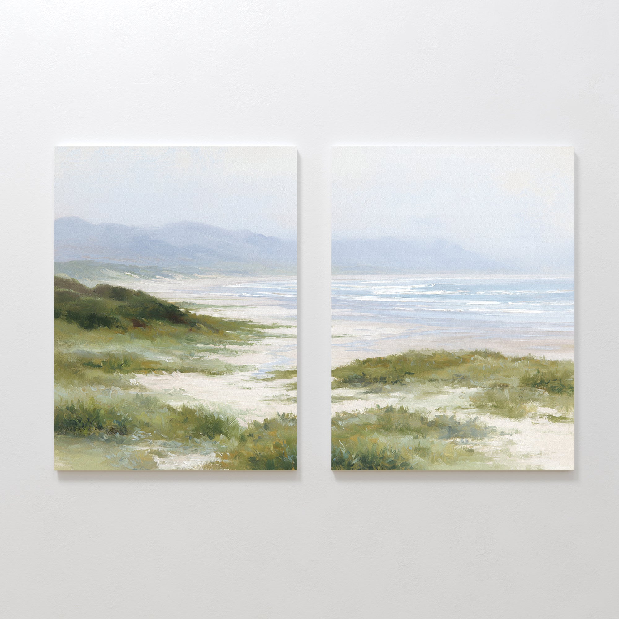 The "Windswept Dunes - Set of 2" features canvas paintings side by side, depicting a calm coastal landscape with sandy paths, grassy dunes, distant hills, and a tranquil ocean beneath a cloudy sky in soft, muted colors.