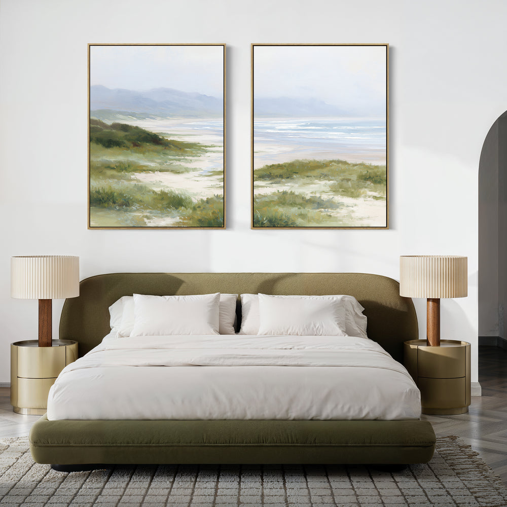 A modern bedroom features a green upholstered bed, white bedding, two gold nightstands with beige lamps, and Windswept Dunes - Set of 2 large landscape canvas prints above the bed, creating a calming atmosphere.