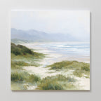 The Windswept Dunes Canvas Art - Square features sandy dunes, coastal grasslands, gentle waves, and misty mountains beneath a soft, cloudy sky, creating a serene and calming atmosphere.