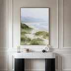 The Windswept Dunes Canvas Art - Vertical hangs above a marble console table adorned with candles, a round container, and modern decor, set against an elegant, light-colored paneled wall.