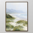 The Windswept Dunes Canvas Art - Vertical depicts gentle waves, sandy beach, and grassy dunes with misty hills beneath a cloudy sky—ideal for adding calming coastal style to any space.