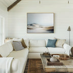 A living room with a large white couch and serene decor, featuring the Winter Plains Canvas Art - Horizontal displayed above.