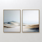 Winter Plains - Set of 2 features framed abstract landscape paintings in soft beige, brown, blue, and white tones, evoking dreamy sand dunes beneath a pale sky—perfect serene wall art for any space.