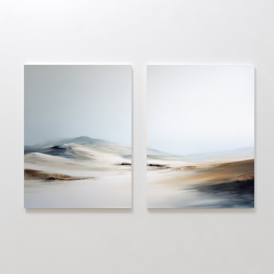 The Winter Plains - Set of 2 features abstract landscape paintings in soft neutrals, with blurred dunes and distant hills under a pale sky, creating serene wall art when displayed together on a white wall.