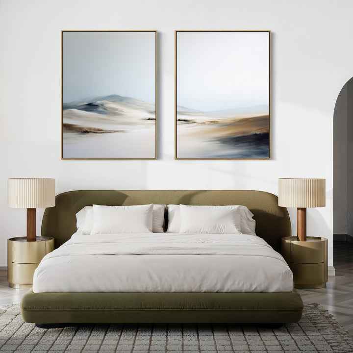 A modern bedroom with an olive green bed, white bedding, two round nightstands with beige lamps, a light rug, and serene wall art featuring Winter Plains - Set of 2 large abstract landscape paintings above the bed.