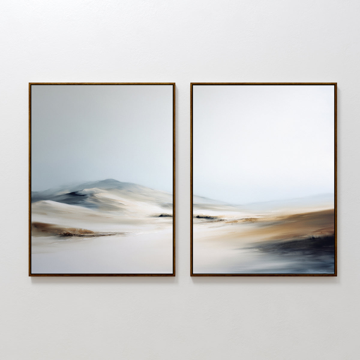 Winter Plains - Set of 2" features framed abstract paintings on a white wall, showing soft, blurred landscapes in neutral tones reminiscent of sand dunes or gentle hills beneath a pale sky.