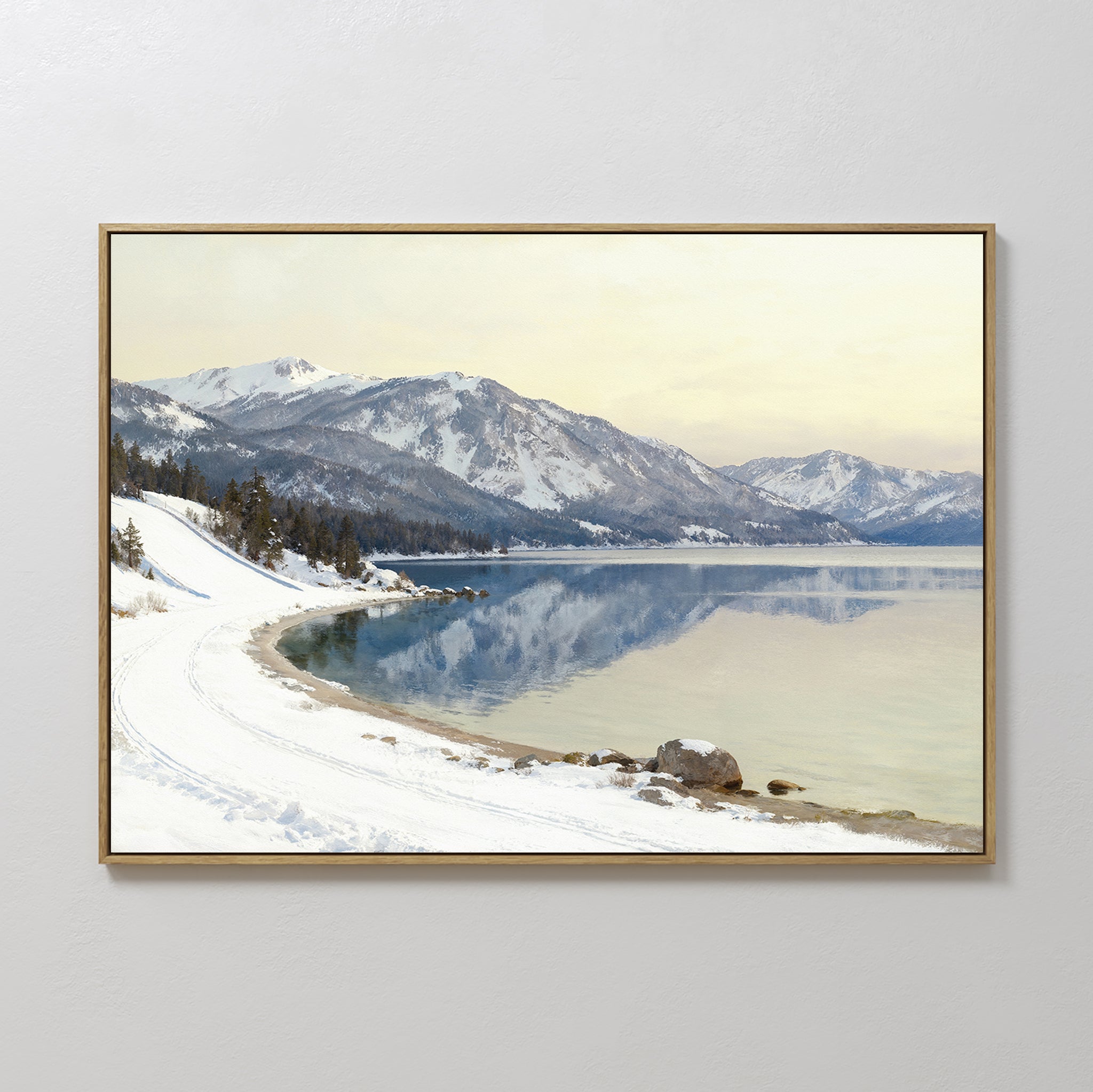 Winter Reflection Canvas Art - Horizontal features a tranquil snowy lakeshore with mountains, pine trees, a calm reflective lake, a pale sky, and tracks in the snow beside the water—ideal serene landscape wall decor.