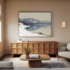 A cozy living room with neutral tones, featuring a wooden coffee table, sofa, sideboard, and a vase with greenery. Above the sofa hangs the Winter Reflection Canvas Art - Horizontal, adding a serene touch to the space.