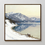 The Winter Reflection Canvas Art - Square features a snowy mountain landscape with pine trees, a winding snow-covered road, and a calm lake reflecting the mountains and sky under soft, diffused light.