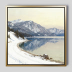 The Winter Reflection Canvas Art - Square features a serene scene of snow-covered mountains, a calm alpine lake mirroring the peaks, and a winding snowy road along the shore beneath a pale sky.
